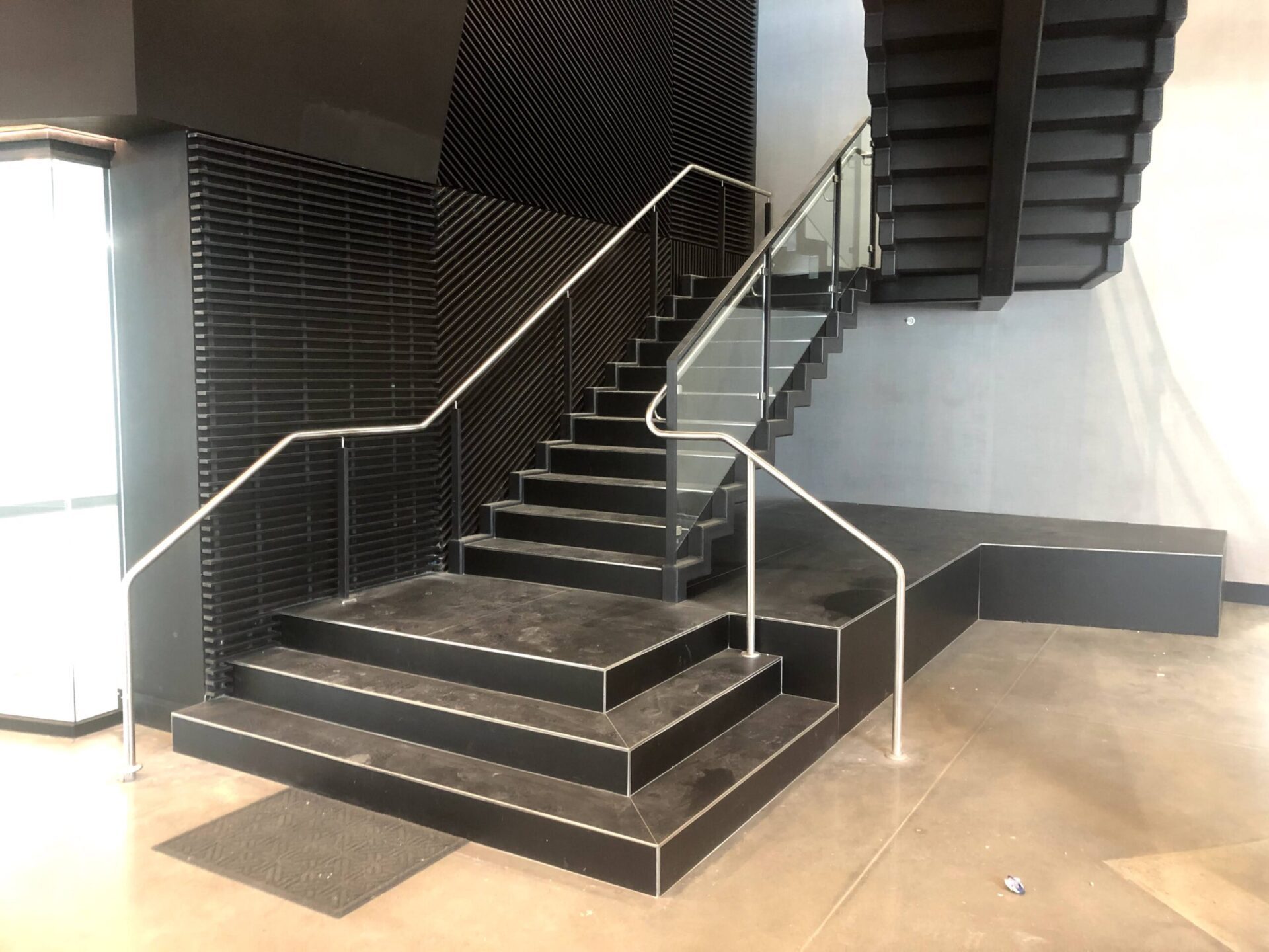 A black staircase with glass and white metal handrails