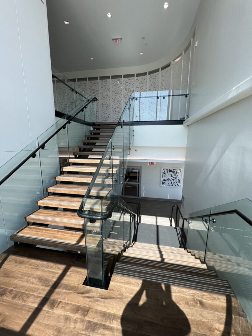 The corner view of a brown staircase with glass and metal handrails