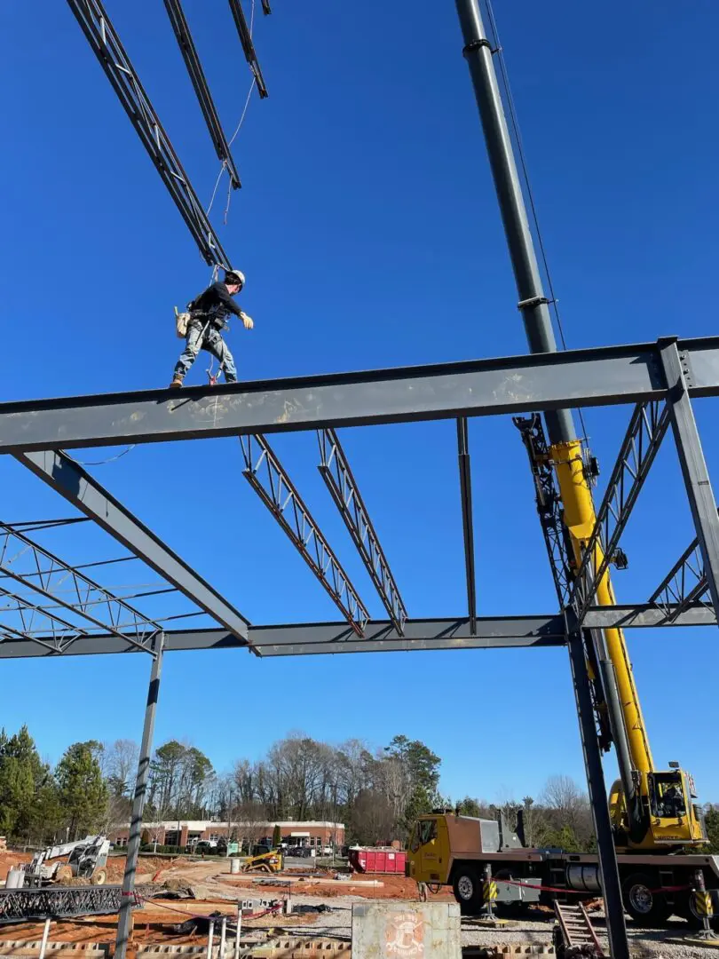 A worker wearing a harness while he walks across a steel beam