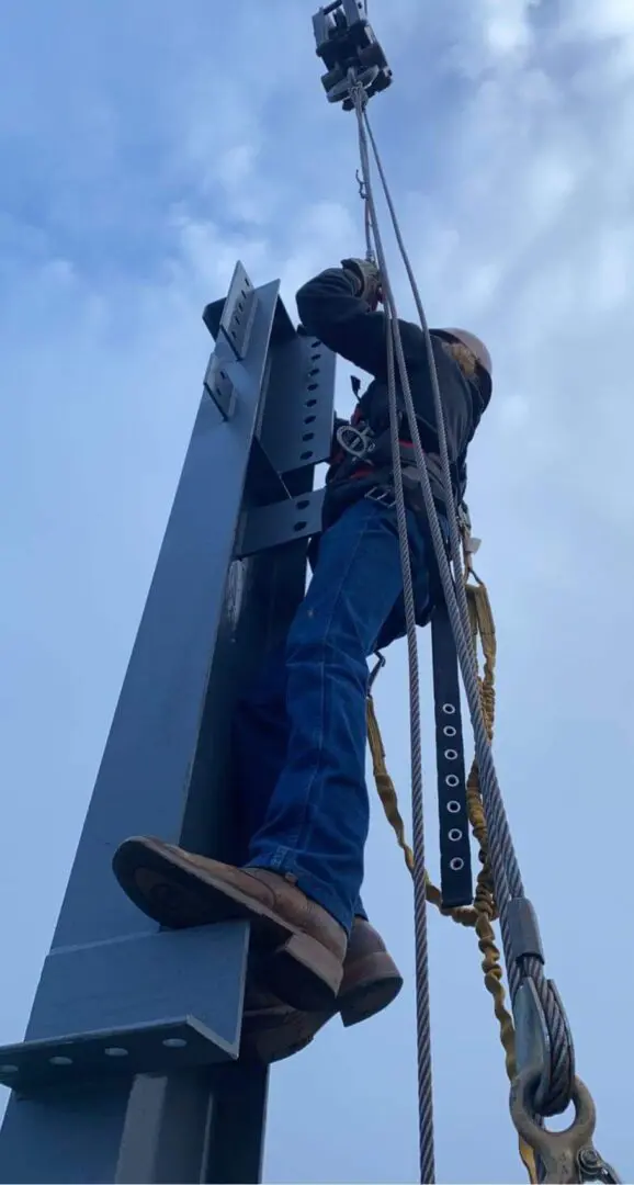 A man connecting a steel beam to a crane
